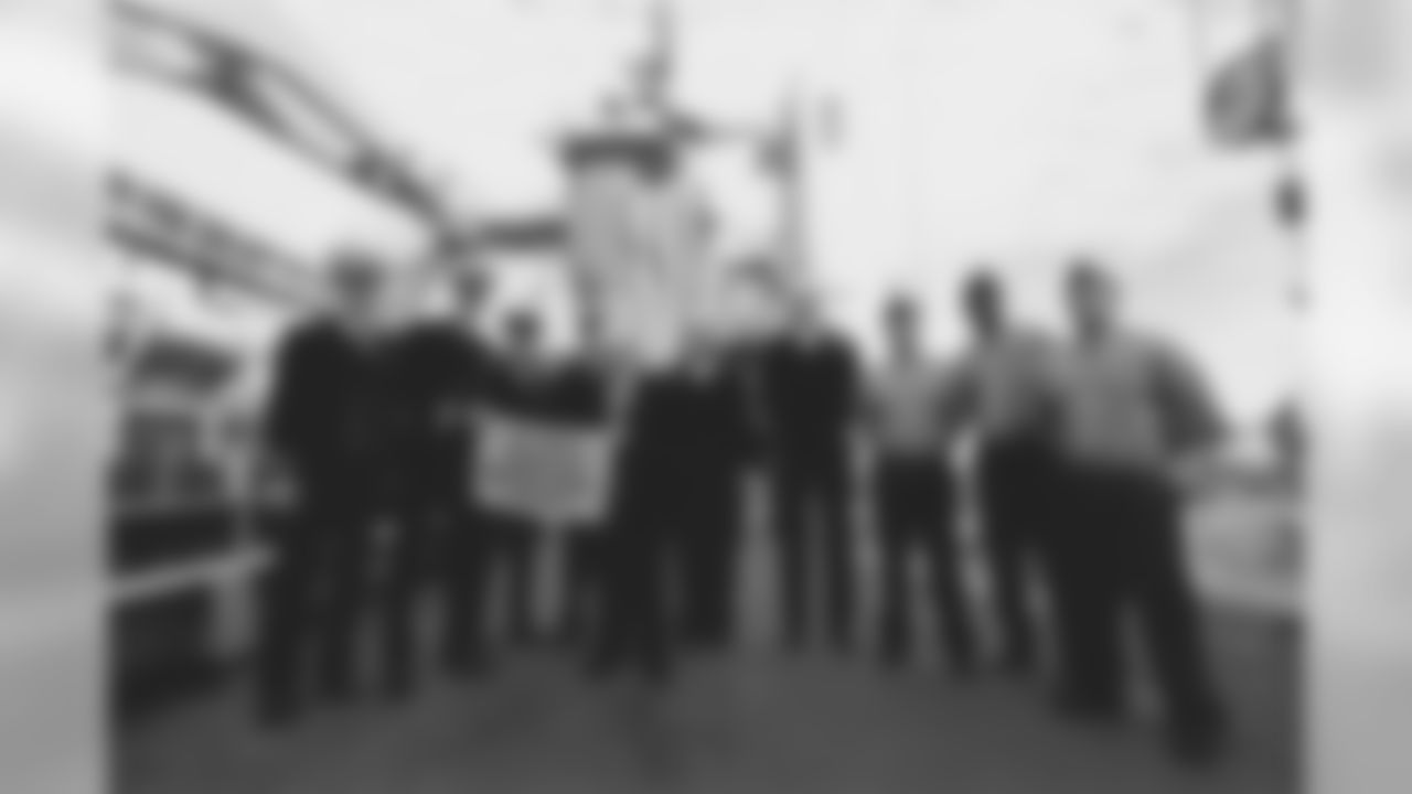 Dan Rooney holding a Terrible Towel with servicemen aboard a Navy vessel.