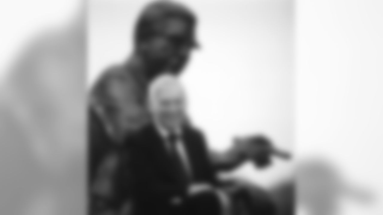 A portrait of Dan Rooney with a statue of his father, Art Rooney behind him.
