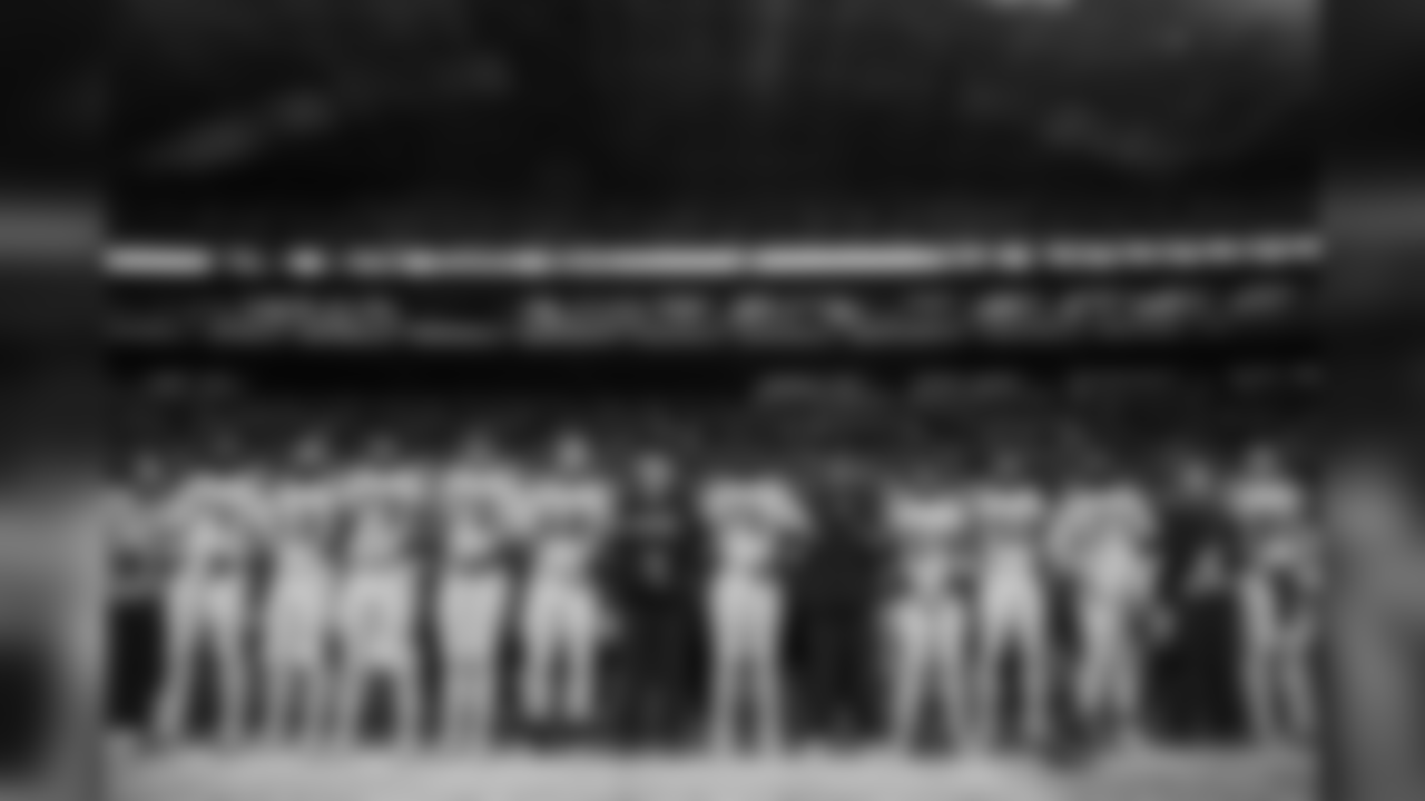 The team stands arm-in-arm during their show of unity during the playing of the national anthem.