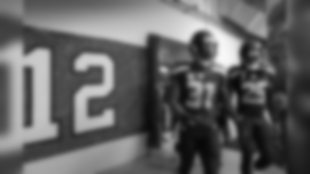 Legion of Boom members Kam Chancellor and Richard Sherman lead the defensive backs past a 12 flag signed by fans as they make their way out of the locker room for pregame warmups.