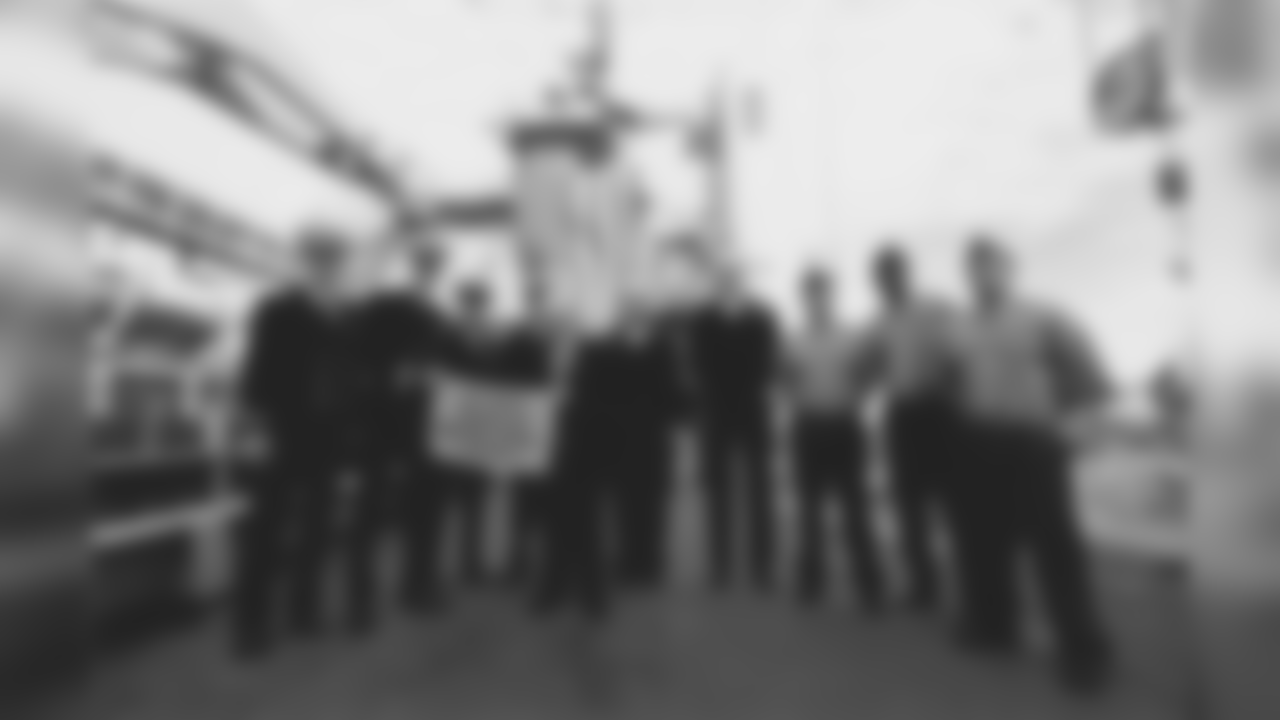 Dan Rooney holding a Terrible Towel with servicemen aboard a Navy vessel.
