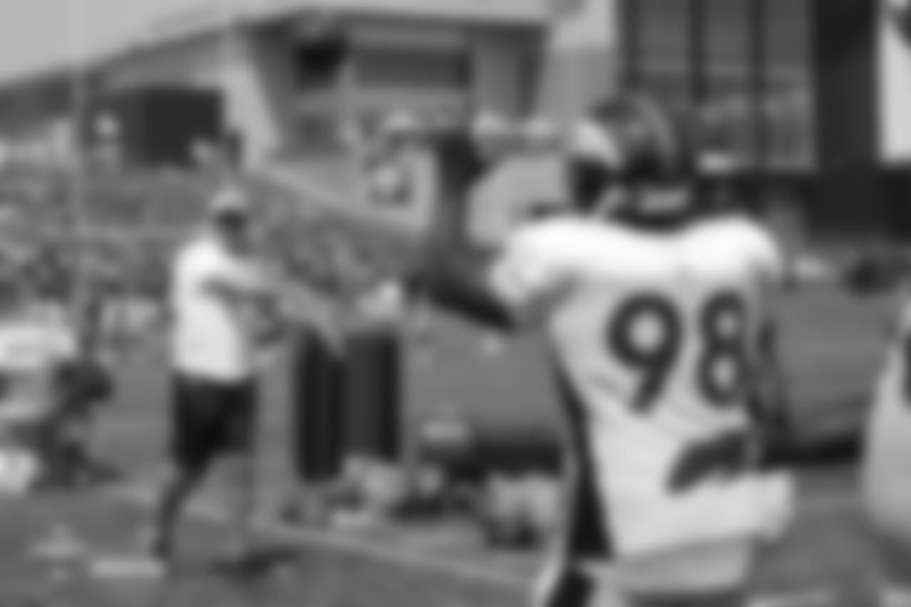 President of Football Operations/General Manager John Elway throws to defensive linemen during a pass-deflecting drill during the ninth day of training camp on August 7, 2018, at UCHealth Training Center.