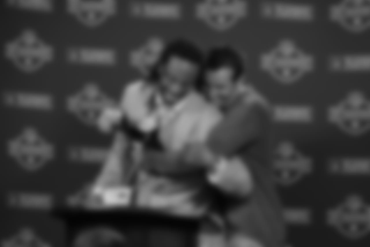 Kurt Warner gives Fitzgerald a hug at the press conference podium after the NFC Championship win