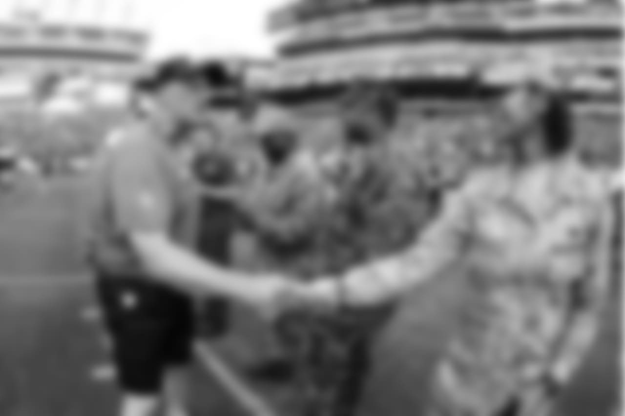 Linebackers coach Ken Flajole shakes hands with military members