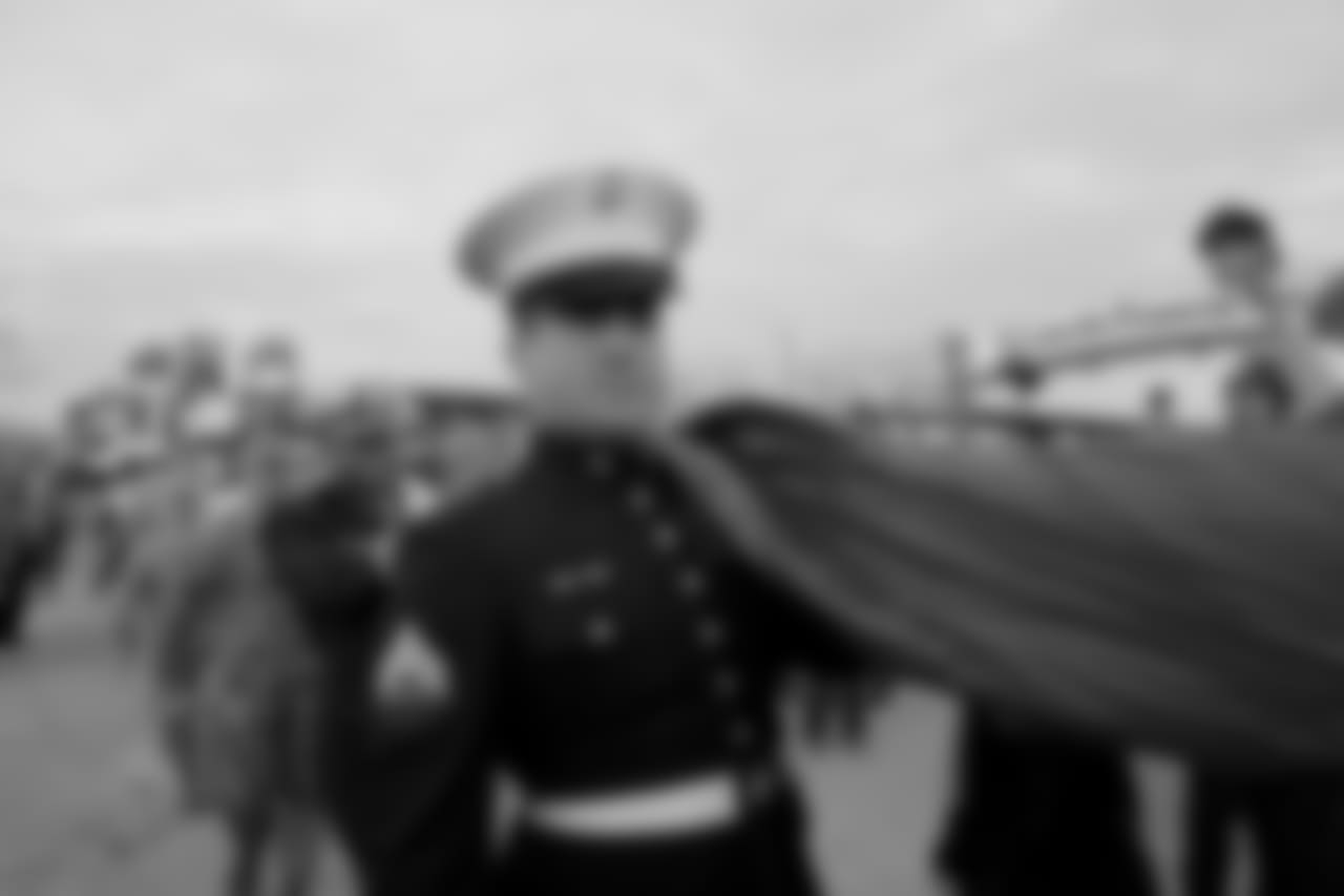 Military members carrying the American Flag into the game