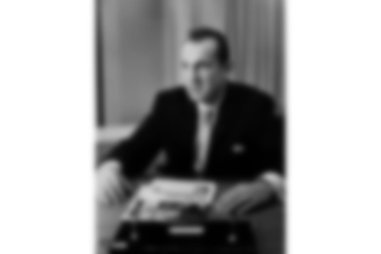 This is a photo of AFL Commissioner, Al Davis seated at his desk with an article about AFL end Gino Cappelletti.