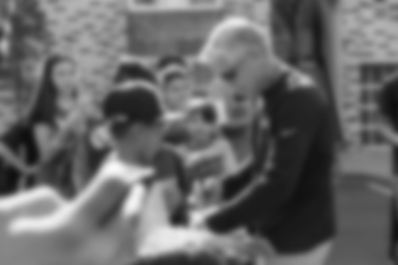 Seahawks head coach Pete Carroll signs autographs for young fans who were gathered by the team's buses at walk thru.