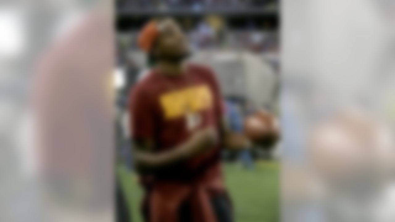 Oklahoma City Thunder's Kevin Durant stands on the sideline peering up at the large video screen playing with a football as the Redskins and Dallas Cowboys warm up before an NFL football game, Sunday, Oct. 13, 2013, in Arlington, Texas. (AP Photo/Tim Sharp)