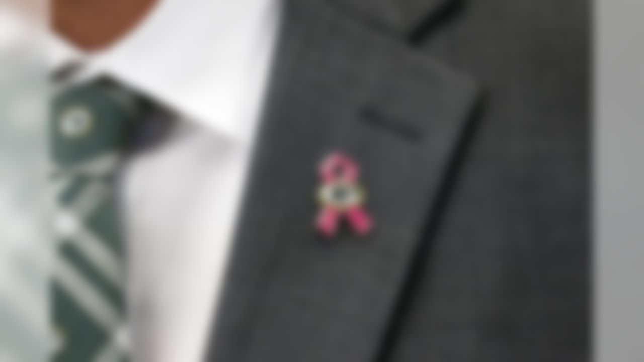 A person on the field wears a Green Bay Packers tie and a cancer awareness pin on their lapel before an NFL football game against the Dallas Cowboys on Sunday, Oct. 8, 2017, in Arlington, Texas.