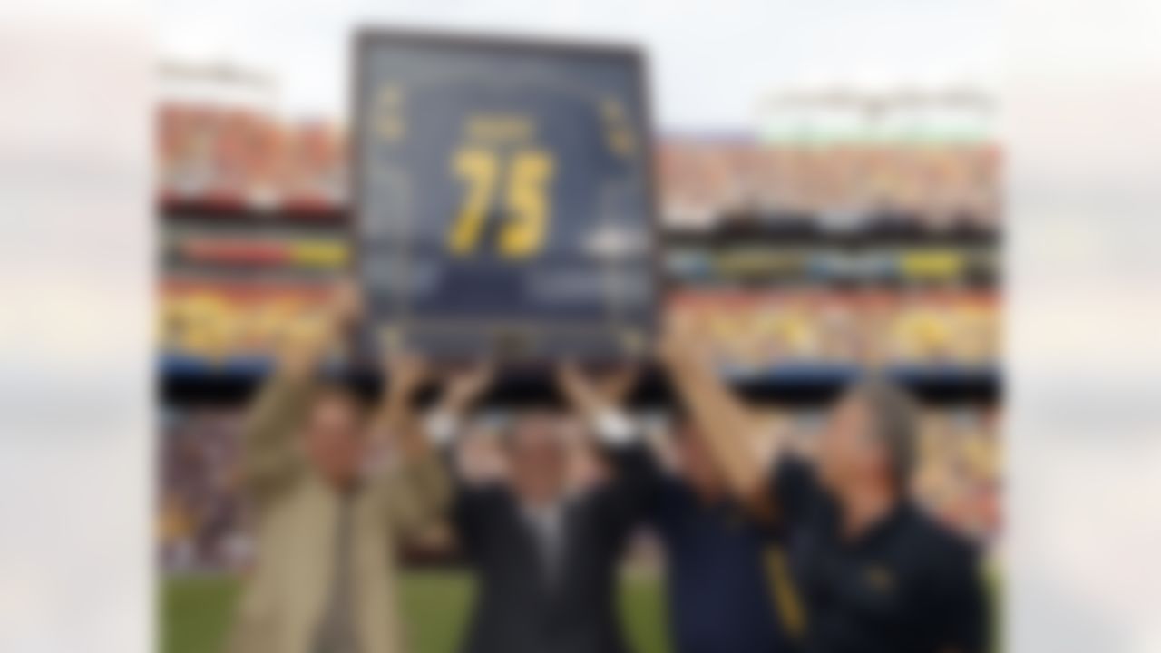 Sam Huff, second from left, Sen. Joe Manchin, D-W.Va., second from right, and others hold a framed jersey aloft as Huff was honored during a ceremony in the first half of an NCAA college football game between West Virginia and James Madison Saturday, Sept. 15, 2012, in Landover, Md. Huff played for West Virginia and went on to play in the the NFL for the New York Giants and the Washington Redskins. (AP Photo/Alex Brandon)