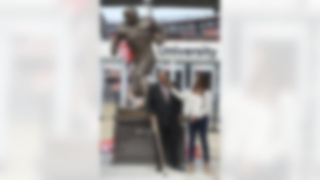 Former Cleveland Browns Pro Football Hall of Famer Jim Brown, center, and his wife Monique, right, is honored with a ceremony and statue outside FirstEnergy Stadium before an NFL football game against the Baltimore Ravens, Sunday, Sept. 18, 2016, in Cleveland. (AP Photo/David Richard)
