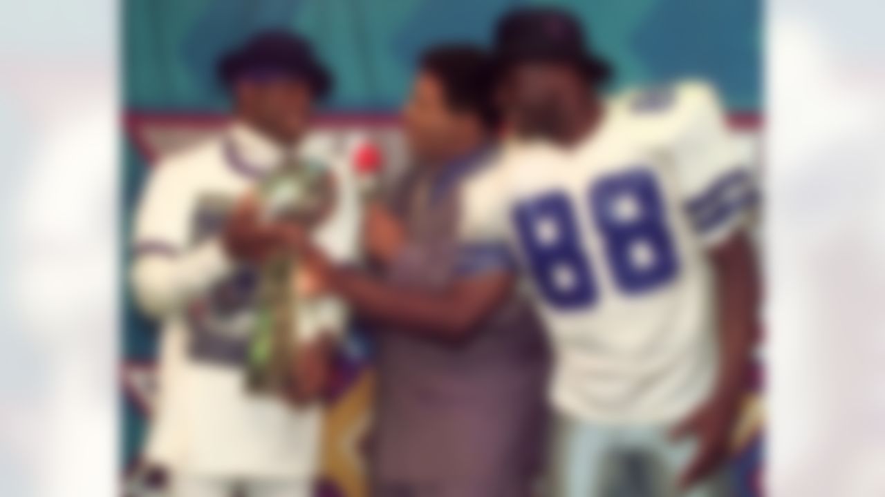 Dallas Cowboys cornerback Deion Sanders, left, and running back Michael Irvin (88) share the Vince Lombardi trophy as NBC commentator Greg Gumbel interviews the two after Super Bowl XXX in Tempe, Ariz., Sunday, Jan. 28, 1996. The Cowboys beat the Pittsburgh Steelers 27-17. (AP Photo/Ron Heflin)