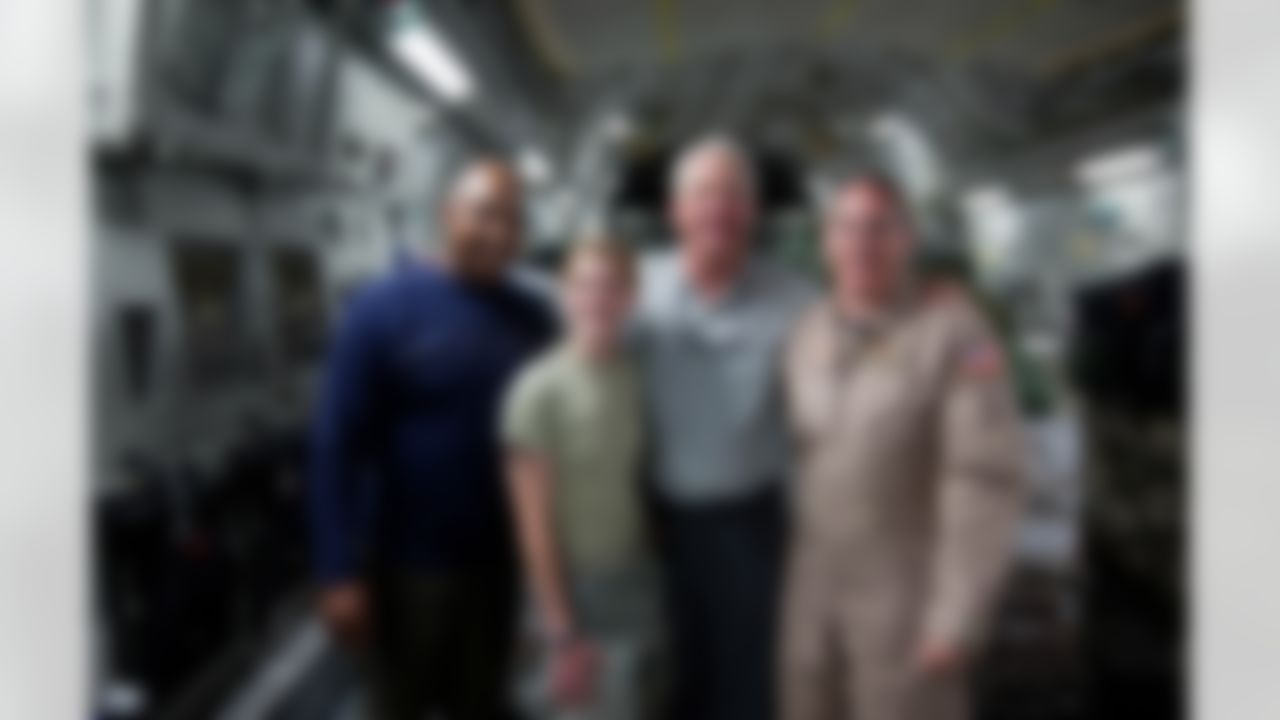 Cincinnati Bengals head coach Marvin Lewis (l) and Carolina Panthers head coach John Fox (2nd r) pose for a photo with crewmembers onboard a US Air Force C-17 cargo jet at Ramstein Air Base in Germany June 29, 2010. This is the first USO tour for Lewis and Fox who are part of a week-long USO/Armed Forces Entertainment tour to Germany and the Persian Gulf. (Fred Greaves/USO)