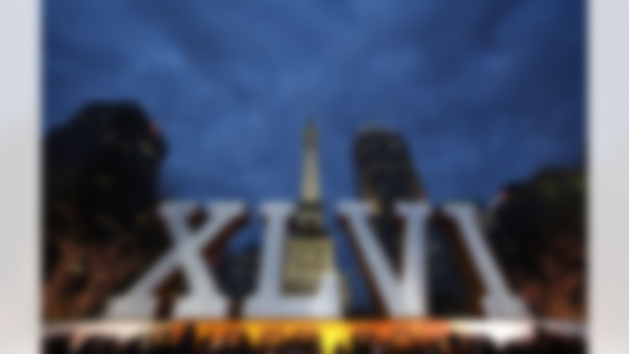 People crowd around the NFL football's Super Bowl XLVI sign on Monument Circle in Indianapolis, Friday, Feb. 3, 2012. The New England Patriots are scheduled to face the New York Giants in NFL football's Super Bowl XLVI on Feb. 5. (AP Photo/Paul Sancya)