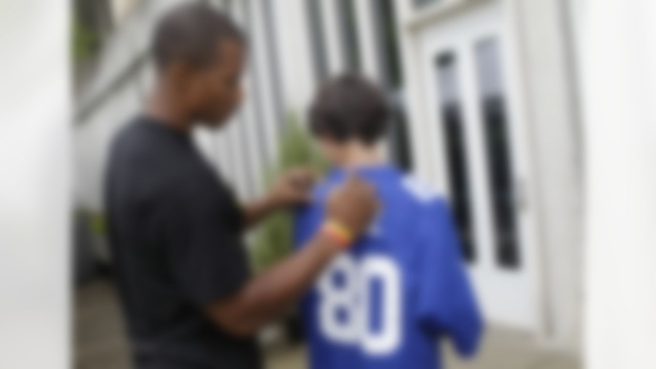 New York Giants wide receiver Victor Cruz, left, autographs Jack Pennington at NFL football training camp in Albany, N.Y., Sunday, July 29, 2012. (AP Photo/Kathy Willens)