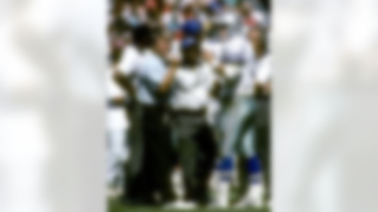 Dallas Cowboys Hall of Fame coach Jimmy Johnson (left) with Hall of Fame quarterback Troy Aikman (right) and wide receiver coach Hubbard Alexander (center) confer on the sideline in a 26-14 win over the Cleveland Browns at Municipal Stadium in Cleveland, Ohio on September 1, 1991. (Al Messerschmidt/NFL)