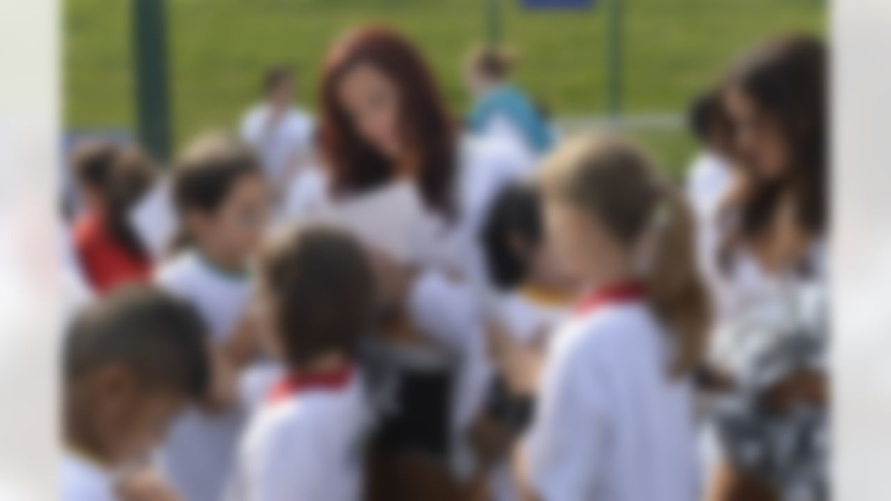 An Oakland Raiders Cheerleader signs her autograph for kids at a football clinic in London. The Oakland Raiders and the Miami Dolphins play in the NFL International Series at Wembley Stadium in London on Sunday, Sept 28. (Sean Ryan/NFL)