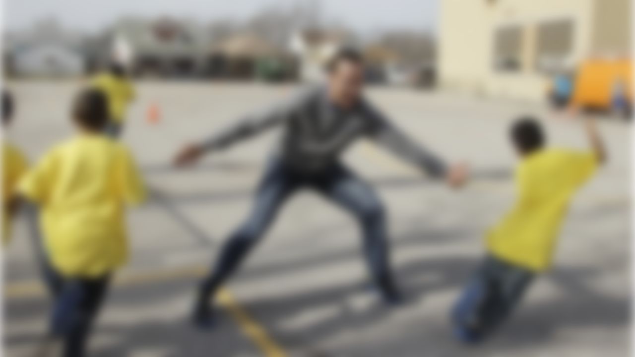 Indianapolis Colts' Peyton Manning, center, plays tag with students at Frederick Douglass School during a BOKS function Friday, Feb. 3, 2012, in Indianapolis. BOKS, which is a before school physical activity program, is in over 300 schools nation-wide. (AP Photo/Darron Cummings)