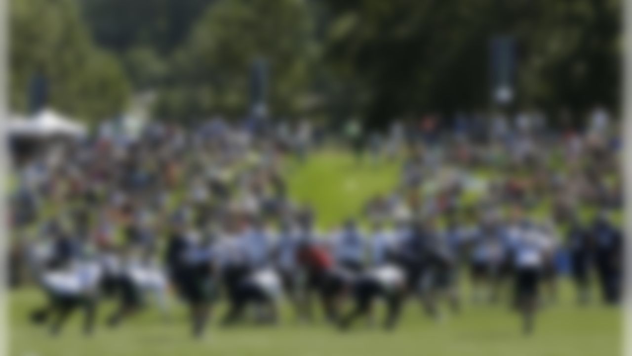 Spectators sit on a grass berm as they watch Seattle Seahawks NFL football training camp, Friday, Aug. 3, 2012, in Renton, Wash. (AP Photo/Ted S. Warren)