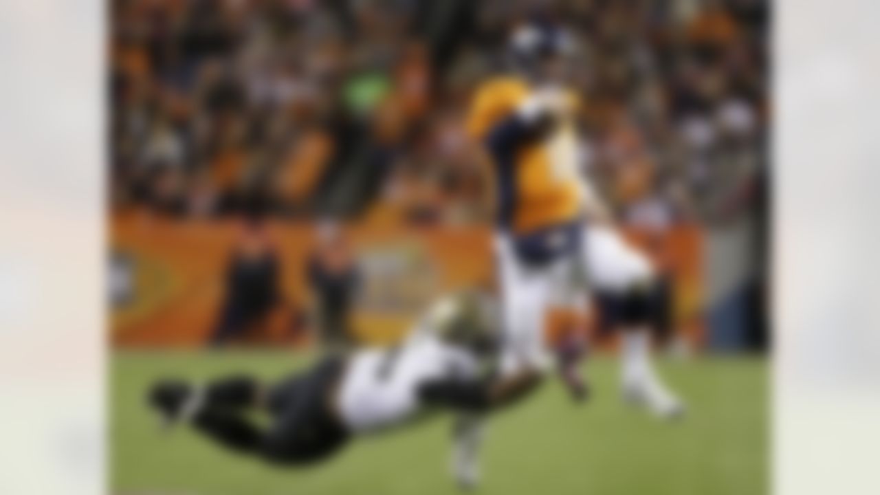 Denver Broncos quarterback Peyton Manning (18) is tripped up by New Orleans Saints defensive tackle Tom Johnson (96) as he runs the ball in the third quarter of an NFL football game, Sunday, Oct. 28, 2012, in Denver. (AP Photo/Jack Dempsey)