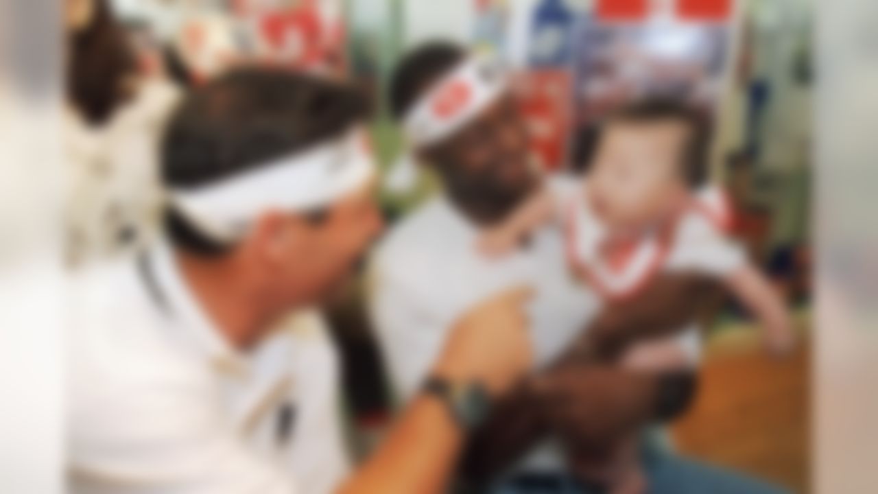 San Francisco 49ers Jerry Rice holds Takashi Okabe, six-months, as his teammate Steve Young tries to coax him during a charity appearance at a Tokyo NFL store on Wednesday, August 2, 1995. The NFL superstars autographed for hundreds of fans to support victims of the Kobe earthquake. The 49ers are in town to play pre-season match against Denver Broncos on Sunday. (AP Photo/Itsuo Inoye)