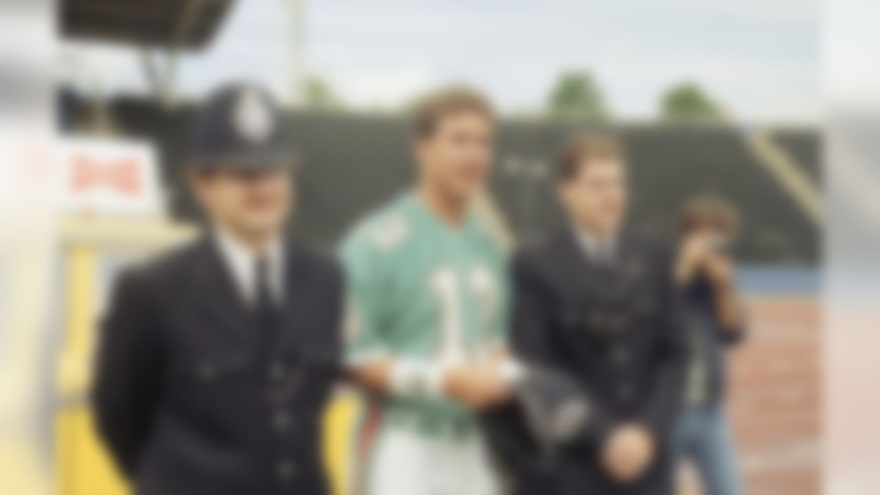 Miami Dolphins quarterback, Dan Marino (13), is pictured during a friendly encounter with two London Police Constables, Dennis Grey, right, and John Lugg, left, during a training session at Crystal Palace,Tuesday, July 26, 1988, London, England. The Miami Dolphins will meet the San Francisco 49?ers in a match at London?s Wembley Stadium, Sunday 31st July. (AP Photo/Doug Jennings)