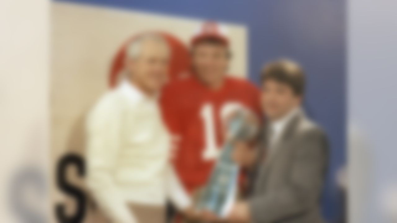 San Francisco 49ers' quarterback Joe Montana, center, is shown holding the Lombardi Super Bowl trophy with coach Bill Walsh, left, and 49ers' owner Edward DeBartolo, Jr., in the locker room at Palo Alto, Calif., Jan. 20, 1985. (AP Photo)