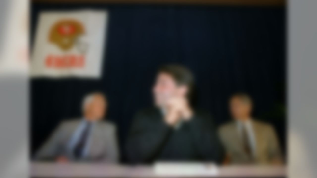 Eddie DeBartolo Jr., center, announces the elevation of coach Bill Walsh, left, to the front office, and the appointment of defensive coordinator George Siefert, right, to replace Walsh as head coach of the world champion San Francisco 49ers, Jan. 26, 1989. The announcement came at a Monterey press conference. (AP Photo/Lance Iverson)