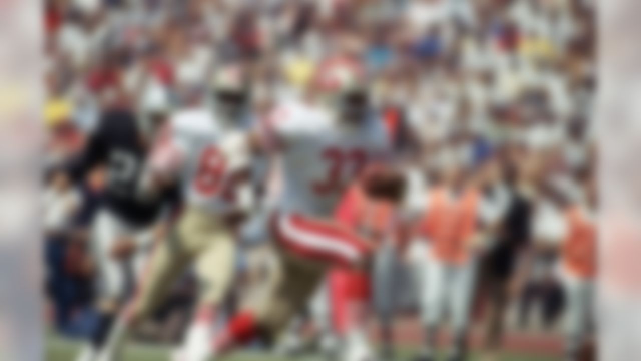 San Francisco 49ers Roger Craig (33) heads for the endzone and first quarter touchdown during NFL game with the Los Angeles raiders at the coliseum in Los Angeles on Sunday, Sept. 22, 1985. Behind Craig are teammate Jerry Rice (80) and Raiders Vann McElroy (26)., 49ers won 34-10. (AP Photo/Doug Pizac)