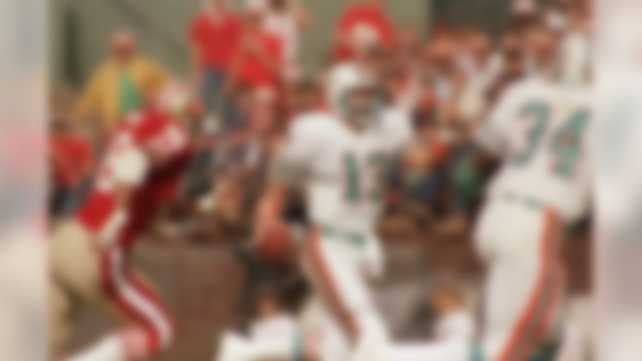 Miami Dolphins quarterback Dan Marino runs with the ball yelling to his teammates as 49ers Dwaine Board closes in during NFL game, Nov. 6, 1985. (AP Photo/Eric Risberg)