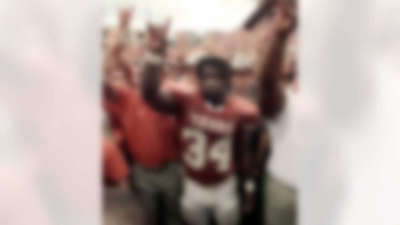 Texas running back Ricky Williams, center, holds up the Longhorns sign as the Texas school song is played in Austin, Texas, Friday, Nov. 27, 1998. Williams rushed for 259 yards, making his the all-time rushing leader. Texas beat Texas A&M 26-24. (AP Photo/Eric Gay)