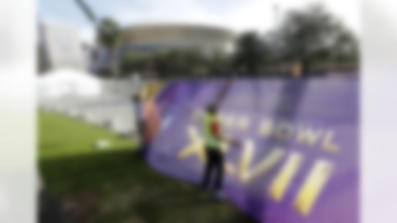 Emmanuel Joiner, left, and Kendrick Mills secure a screen over a fence that surrounds the Mercedes-Benz Superdome as crews prepare for the NFL Super Bowl XLVII football game on Sunday, Jan. 27, 2013, in New Orleans. The Baltimore Ravens and San Francisco 49ers are scheduled to play in Super Bowl XLVII on Sunday, Feb. 3. (AP Photo/Patrick Semansky)