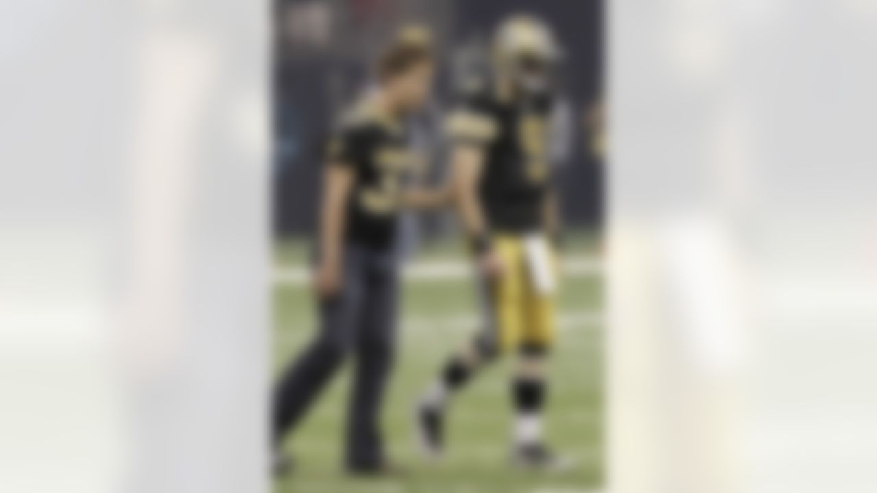 Former New Orleans Saints football player Steve Gleason walks off the field with New Orleans Saints quarterback Drew Brees (9) before the first half of an NFL football game against the Houston Texans, Sunday, Sept. 25, 2011, in New Orleans. (AP Photo/Gerald Herbert)