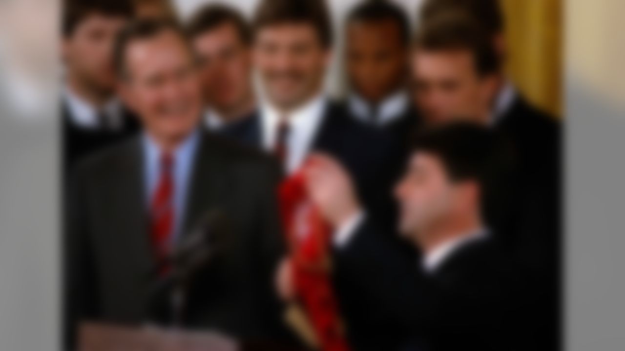 Super Bowl champions, San Francisco 49ers owner Eddie DeBartolo, right, presents President George Bush with a scarf for his dog, Millie, in the White House in Washington, Feb. 27, 1990. Quarterback Joe Montana, top right, and linebacker Michael Walter, center, join their teammates. (AP Photo/Marcy Nighswander)