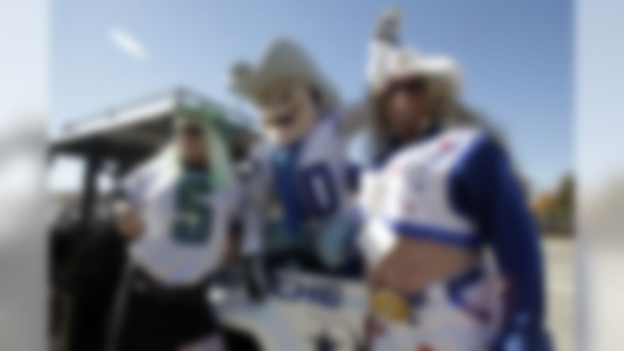 Philadelphia Eagles fan Jimmy Pyle and Dallas Cowboys fan Richard Welch, right, both of St. Petersburg, Fla., pose for a photo with Cowboys mascot Rowdy, center, as they tailgate before an NFL football game, Thursday, Nov. 27, 2014, in Arlington, Texas. (AP Photo/Tim Sharp)