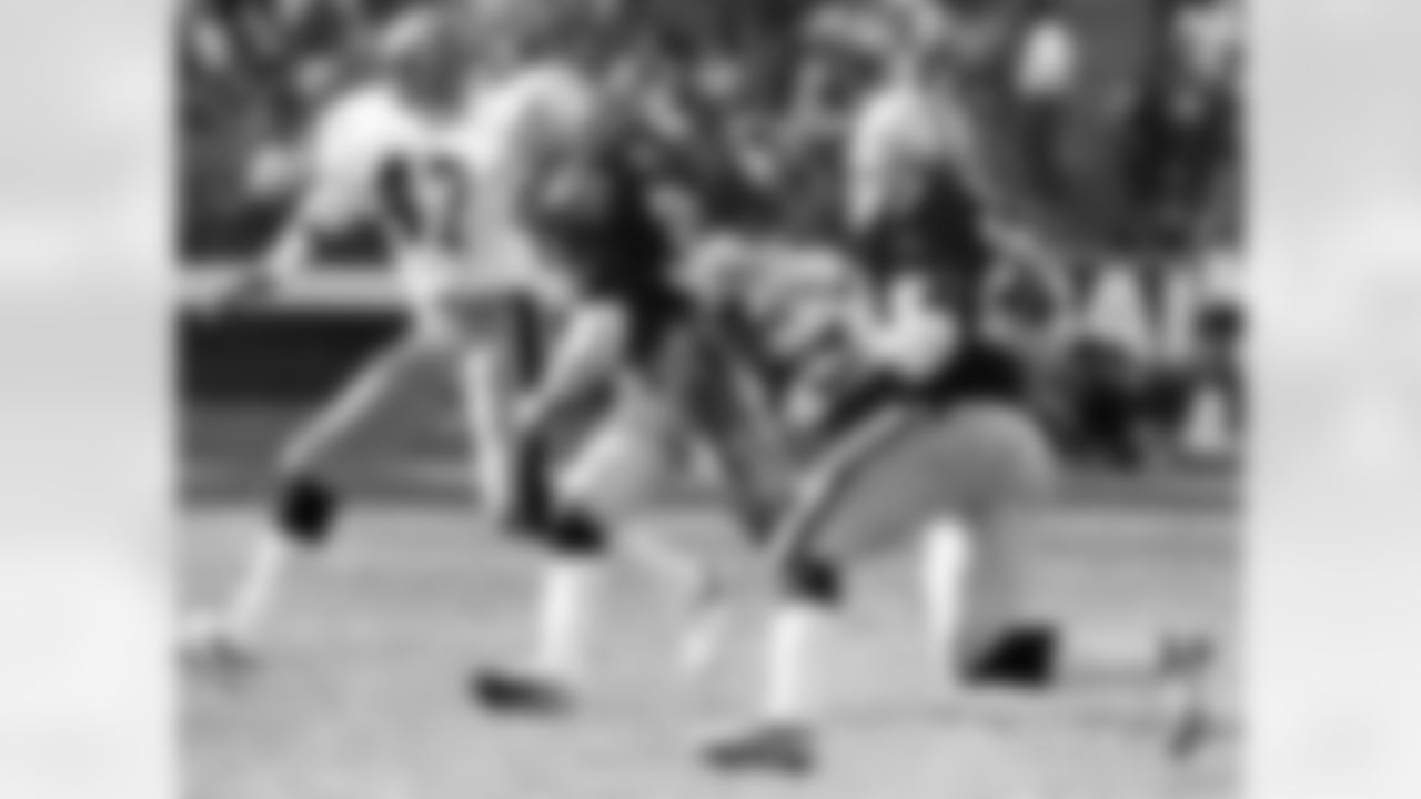 Los Angeles Raiders running back Frank Hawkins (27) follows the blocks of running back Marcus Allen (32) against Pittsburgh Steelers cornerback Mel Blount (47), the latter two players both members of the Pro Football Hall of Fame, during the 1983 AFC Divisional Playoff Game on January 1, 1984. (National Football League)