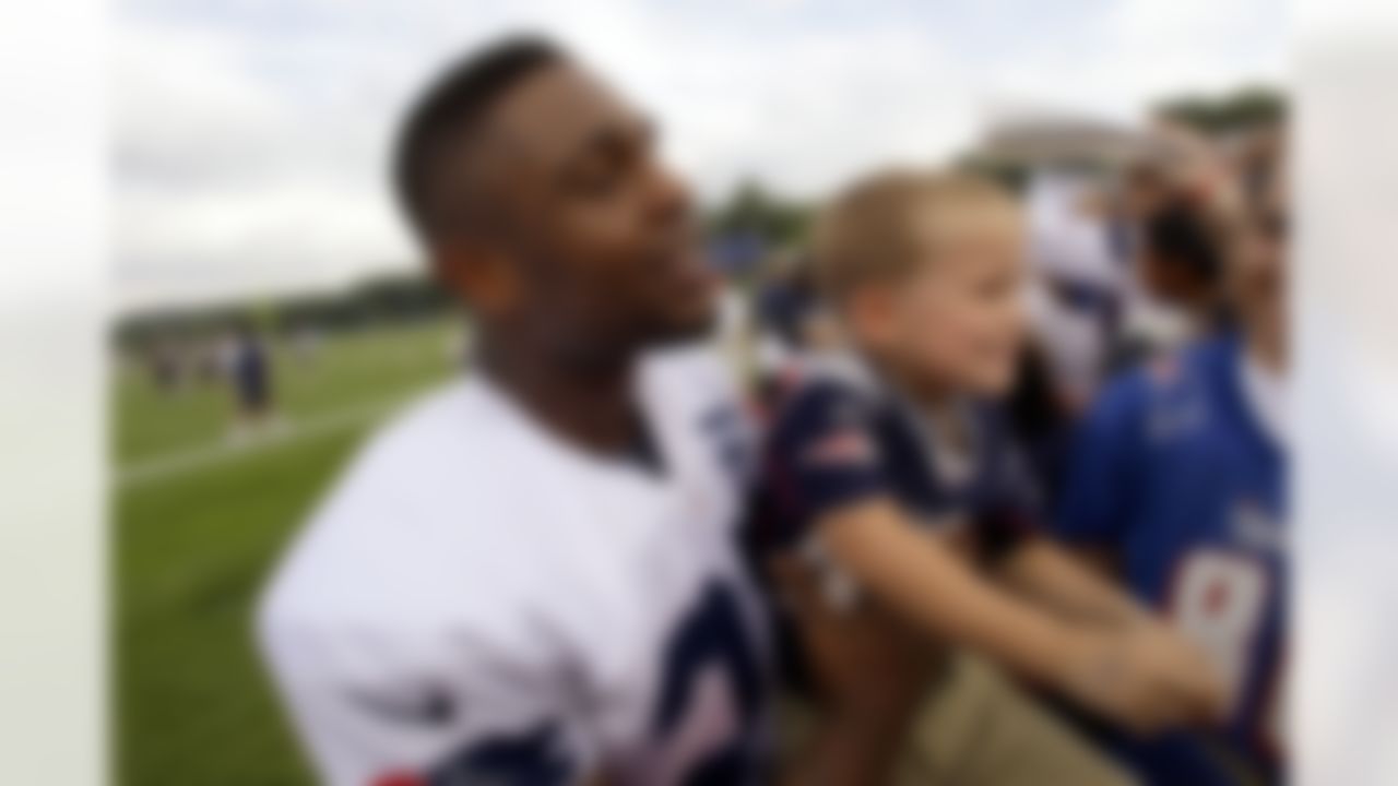New England Patriots running back Stevan Ridley (22) hands a child back to his parents after posing for a picture after practice on the first day of training camp at the NFL football team's facility in Foxborough, Mass., Thursday, July 26, 2012. (AP Photo/Stephan Savoia)