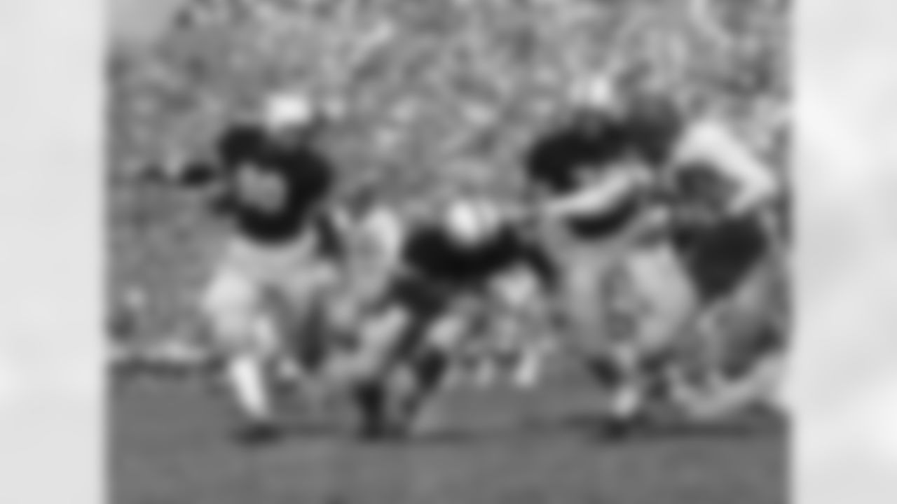 Texas Christian University quarterback Ray McKown places a good stiff arm to Texas A&M back Yale Larry as he goes around his left end for a four yard gain in first quarter of game Oct. 20, 1951 in Fort Worth, Texas. Coming in to aid Larry on the stop is center Jim Fowler (90) and Tackle Ralph Hudeck coming in behind. (Associated Press)