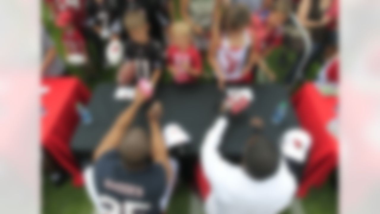 Arizona Cardinals' Kerry Rhodes, left, and Michael Adams sign autographs for fans prior to NFL training camp football practice at Northern Arizona University on Saturday, July 28, 2012, in Flagstaff, Ariz.(AP Photo/Ross D. Franklin)