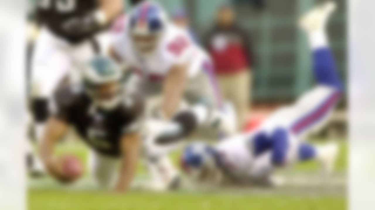 Philadelphia Eagles quarterback Donovan McNabb, left, dives for a two-yard gain ahead of tackle attempts by New York Giants saftey Omar Stoutmire, right, and defensive end Michael Strahan (92) during the fourth quarter Sunday, Nov. 16, 2003, in Philadelphia. The Eagles won 28-10. (AP Photo/Chris Gardner)