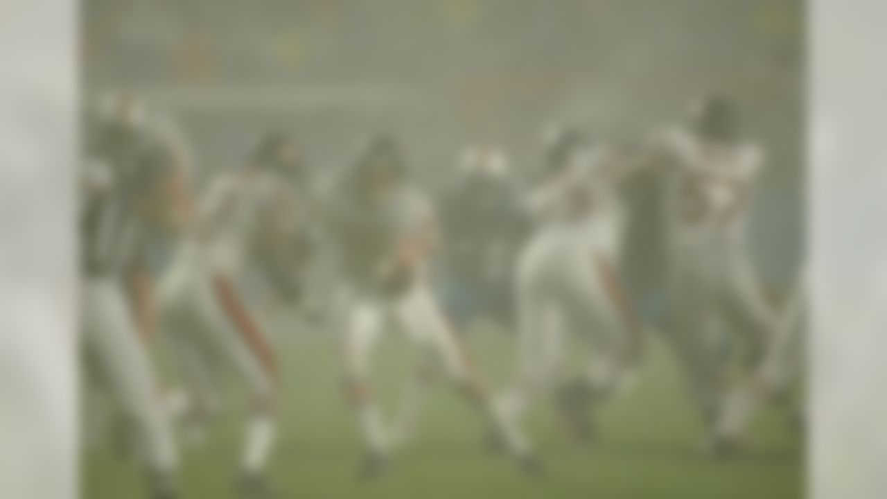 Chicago Bears quarterback Jim Miller (15) hands the ball off to running back Leon Johnson (32) as Kevin Dogins (73) and Olin Kreutz (57) block Miami Dolphins players as Dolphins Justin Seaverns looks for a opening in the tropical downpour of rain during the first half of the Monday, Dec. 9, 2002, game in Miami. (AP Photo/Gary Rothstein)