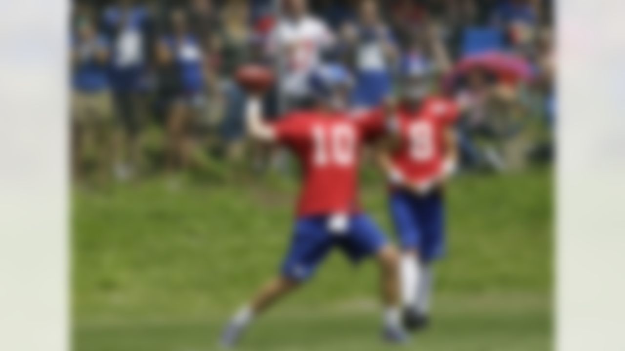 Spectators watch from behind a chain link fence as New York Giants quarterback Eli Manning passes during a workout at the New York Giants NFL football training camp in Albany, N.Y., Sunday, July 29, 2012. Backup quarterback David Carr (8) watches the play. (AP Photo/Kathy Willens)