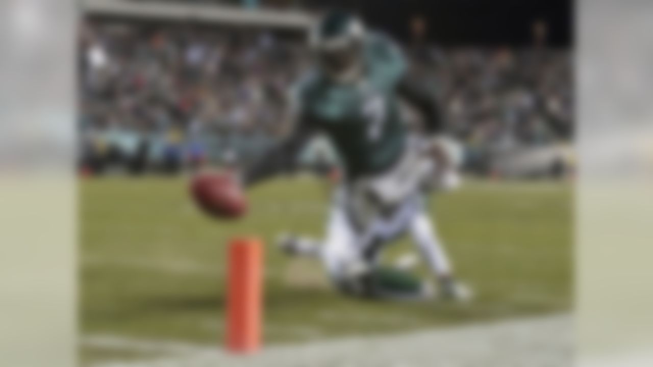 In this Dec. 18, 2011, file photo, Philadelphia Eagles quarterback Michael Vick (7) scores a touchdown as New York Jets defensive back Kyle Wilson can't make the stop in the first half of an NFL football game in Philadelphia. In the 13 years since his arrival as the fastest man on the field who also happened to have the best arm, Vick's impact has been felt in the way quarterbacks and offenses evolve in high school, college, and eventually, the pros. (AP Photo/Matt Slocum, File)