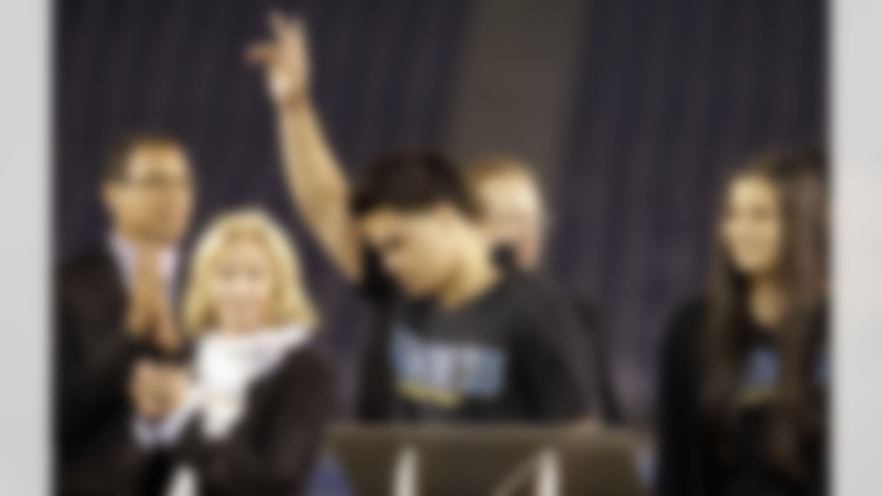 Tyler Seau, center, the son of Junior Seau, reacts to fans during a public memorial service for the late NFL football player Junior Seau at Qualcomm Stadium Friday, May 11, 2012, in San Diego. At rear are pastor Miles McPherson, left, San Diego Chargers owner Dean Spanos, second from right, his wife Susie Spanos, second from left, and Seau's daughter, Sydney Seau. Seau committed suicide on May 2 at his Oceanside, Calif., home. He played parts of 20 seasons in the NFL, with the San Diego Chargers, Miami Dolphins and New England Patriots. (AP Photo/Gregory Bull)