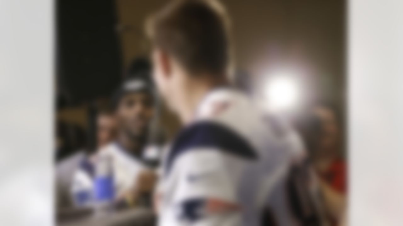 New England Patriots safety Devin McCourty, left, uses a television microphone to ask a question of tight end Rob Gronkowski, center, during a news conference Wednesday, Jan. 28, 2015, in Chandler, Ariz. The Patriots play the Seattle Seahawks in NFL football Super Bowl XLIX Sunday, Feb. 1, in Phoenix. (AP Photo/Mark Humphrey)
