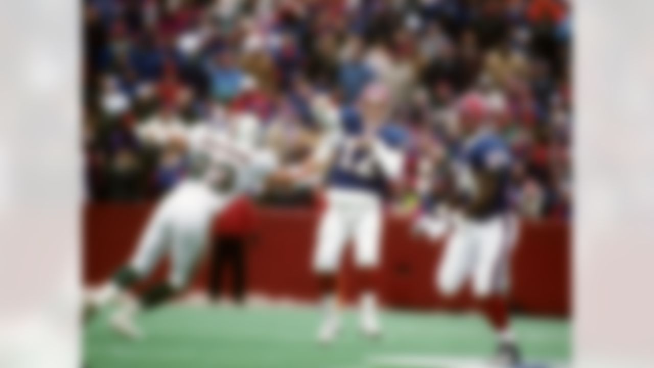 Hall of Fame quarterback Jim Kelly of the Buffalo Bills throws a pass to running back Thurman Thomas while trying to avoid the pressure from Miami Dolphins defensive end Trace Armstrong during the Bills 37-22 victory over the Miami Dolphins in the 1995 AF 1995 AFC Wild Card Playoff Game - Miami Dolphins vs Buffalo Bills - December 30, 1995 (National Football League)