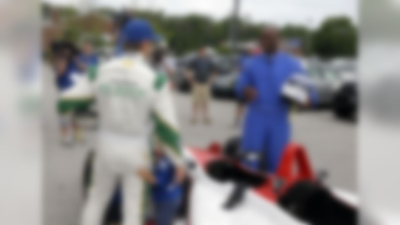 Indianapolis Colts receiver Reggie Wayne, right, talks with race driver Ed Carpenter after he arrived in a two-seat IndyCar driven by Carpenter as he and other players arrived for the NFL team's football training camp in Anderson, Ind., Wednesday, July 23, 2014.  (AP Photo/Michael Conroy)