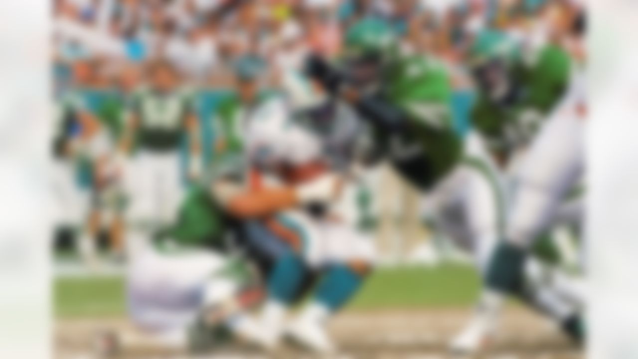 New York Jets Ronnie Lotts (42), right, and Jeff Legeman (56) bring down Miami Dolphins Mark Higgs (21), center, during first half action at Joe Robbie Stadium in Miami on Sunday, Sept. 12, 1993. (AP Photo/Hans Deryk)