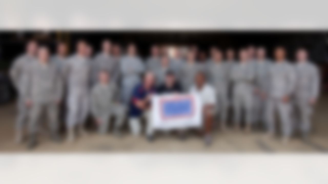 Carolina Panthers head coach John Fox(r behind USO banner), Minnesota Vikings head coach Brad Childress (c behind banner), Cincinnati Bengals head coach Marvin Lewis (r behind banner) and Philadelphia Eagles head coach Andy Reid (back row 6th r wearing sunglasses) pose for a photo with the 435th Air Mobility Squadron at Ramstein Air Base in Germany during a USO/Armed Forces Entertainment tour stop on June 30, 2010. (Fred Greaves/USO)