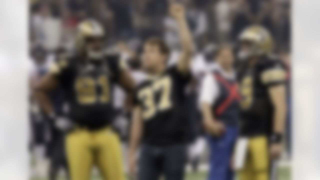 Former New Orleans Saints football player Steve Gleason raises his hand to the crowd as Saint quarterback Drew Brees (9) and defensive end Will Smith (91) look on before the first start of NFL football game against the Houston Texans in New Orleans. (AP Photo/Gerald Herbert)